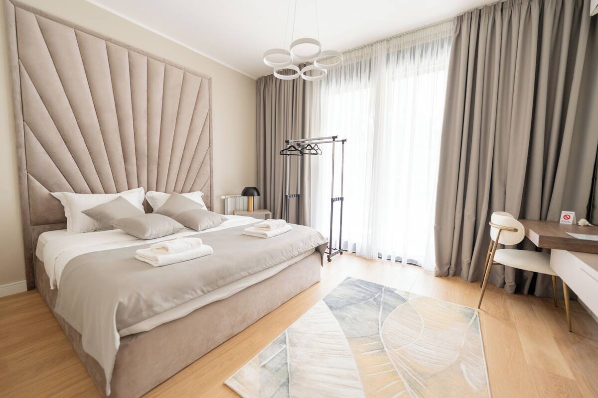 Un dormitorio moderno con una cama grande, un escritorio, una silla y un perchero.