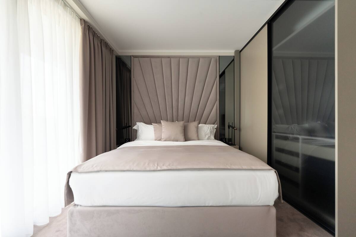 Una habitación de hotel moderna con una cama grande, una puerta corredera de cristal y vistas a la ciudad.