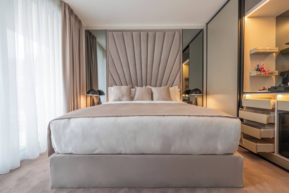 Una habitación de hotel moderna con una cama grande, mesitas de noche, un espejo y un armario empotrado.