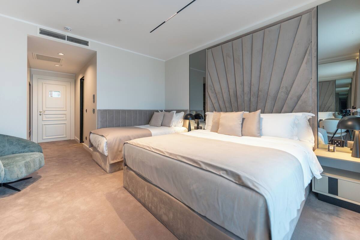Una habitación de hotel moderna con dos camas, un espejo grande y una zona de estar.