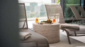 Ein stilvoller Lounge-Bereich mit einem runden Tisch, zwei Stühlen und Blick auf die Stadt durch große Fenster.