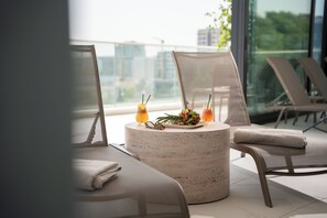 A modern lounge area with a round table, two chairs, and a view of the cityscape through large windows. - New Belgrade Premium Hotel (Belgrade)