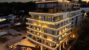 Ein mehrstöckiges Hotel mit modernem Design, mit Balkonen und einer gut sichtbaren Beschilderung für das New Belgrade Premium Hotel.
