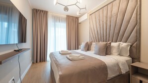 A modern hotel room with a large bed, a flat-screen TV, a bedside table, and a built-in headboard. - New Belgrade Premium Hotel (Belgrade)