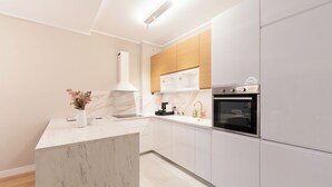 A modern kitchen with white cabinetry, a marble island, and stainless steel appliances. - New Belgrade Premium Hotel (Belgrade)