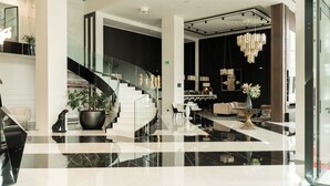 Eine moderne Lobby mit einer geschwungenen Treppe, einem Empfangsbereich und einer Sitzecke mit einer Chandelier.