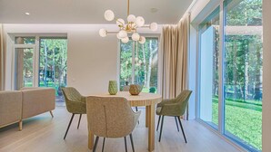 Een moderne eetruimte met een ronde tafel, vier stoelen en een kroonluchter.
