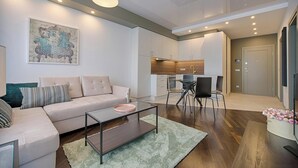 Een moderne woonkamer met een bank, salontafel en een eethoek met stoelen.
