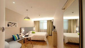 Een moderne hotelkamer met een bed, een zithoek met een laptop en een kleine tafel.
