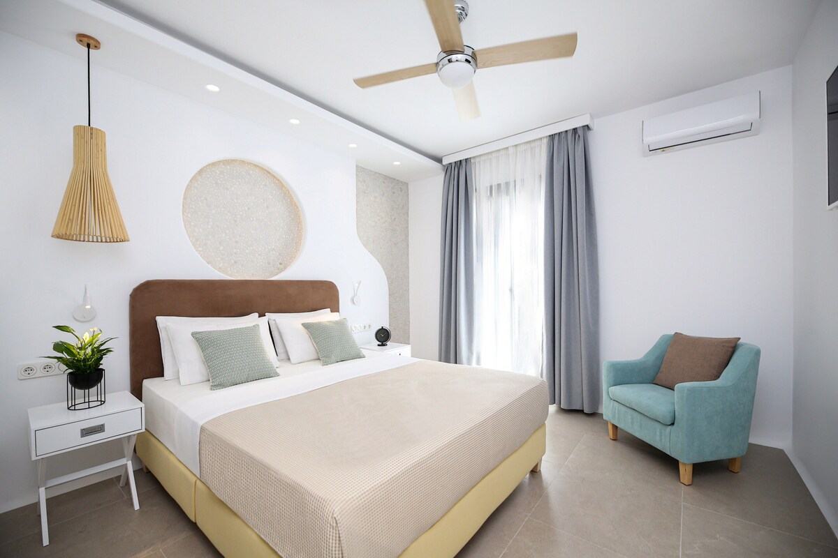 A modern bedroom with a bed, bedside table, nightstand, and a ceiling fan.