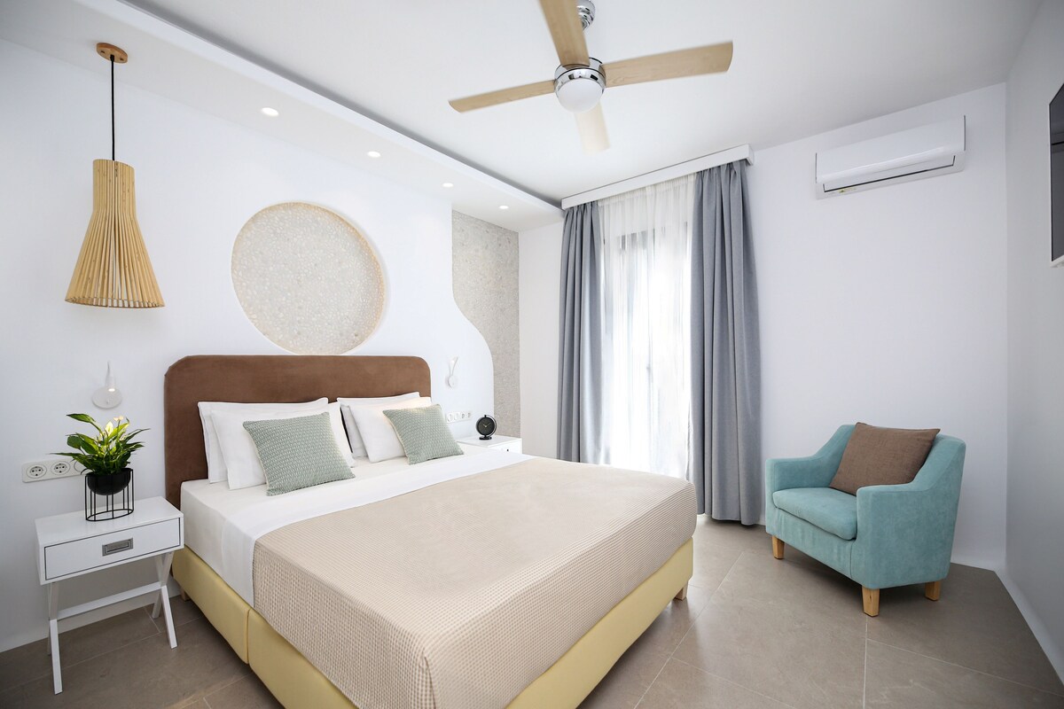 A modern bedroom with a bed, bedside table, nightstand, and a ceiling fan.