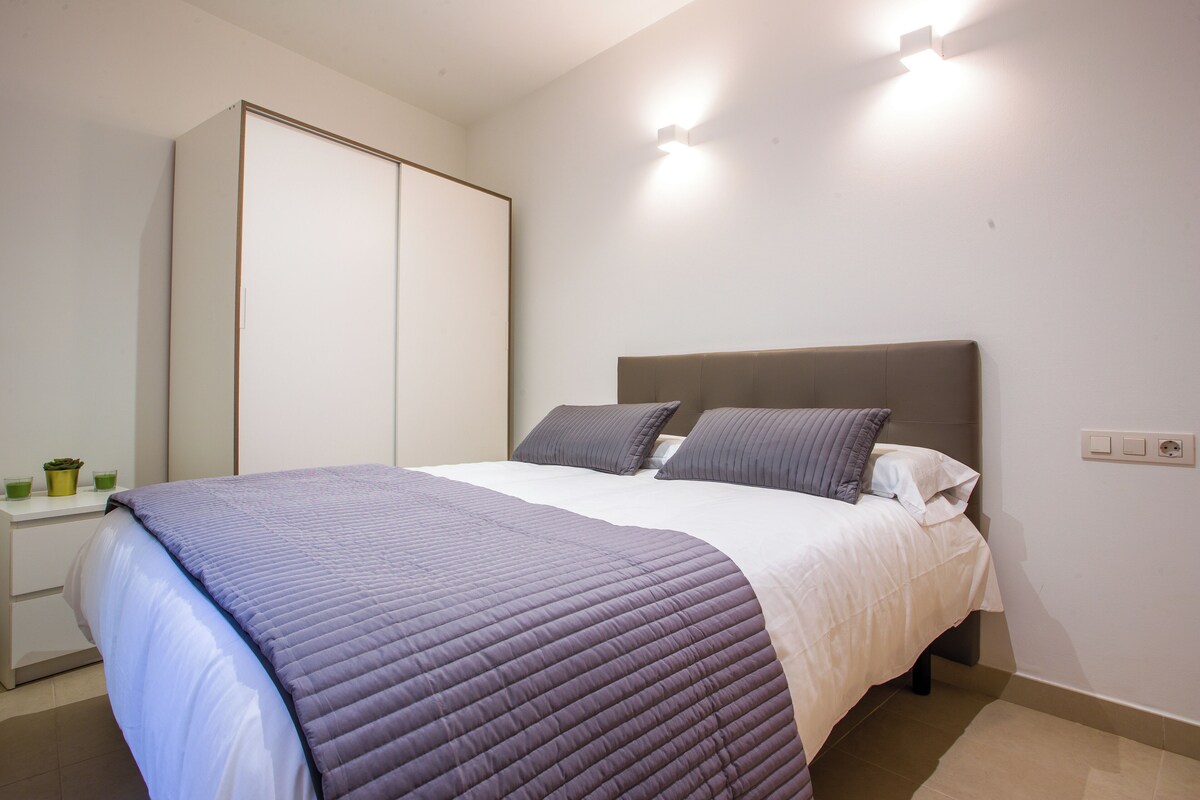 A bedroom with a bed, a wardrobe, and a bedside table.