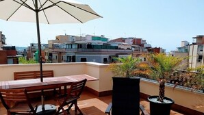 A rooftop terrace with a table and chairs, a chair, and a potted plant. - Feriapiso Apartments Palmer (L'Hospitalet de Llobregat)