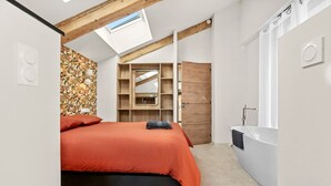 Ein Schlafzimmer mit Bett, einer eingebauten Ablage, einem Oberlicht und einem Badezimmer mit Badewanne.
