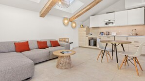 Ein modernes Wohnzimmer mit einer Couch, einem runden Couchtisch und einem Essbereich mit Stühlen.