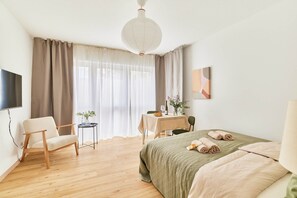 Ein Hotelzimmer mit einem Bett, einem Sessel, einem Tisch mit einer Pflanze und einem Fernseher.