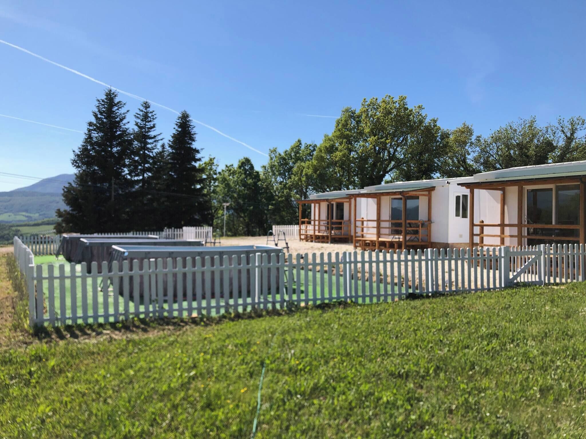 A mobile home with a fenced yard, a pool, and a view of trees and mountains.