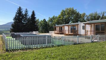 A mobile home with a fenced yard, a pool, and a view of trees and mountains.
