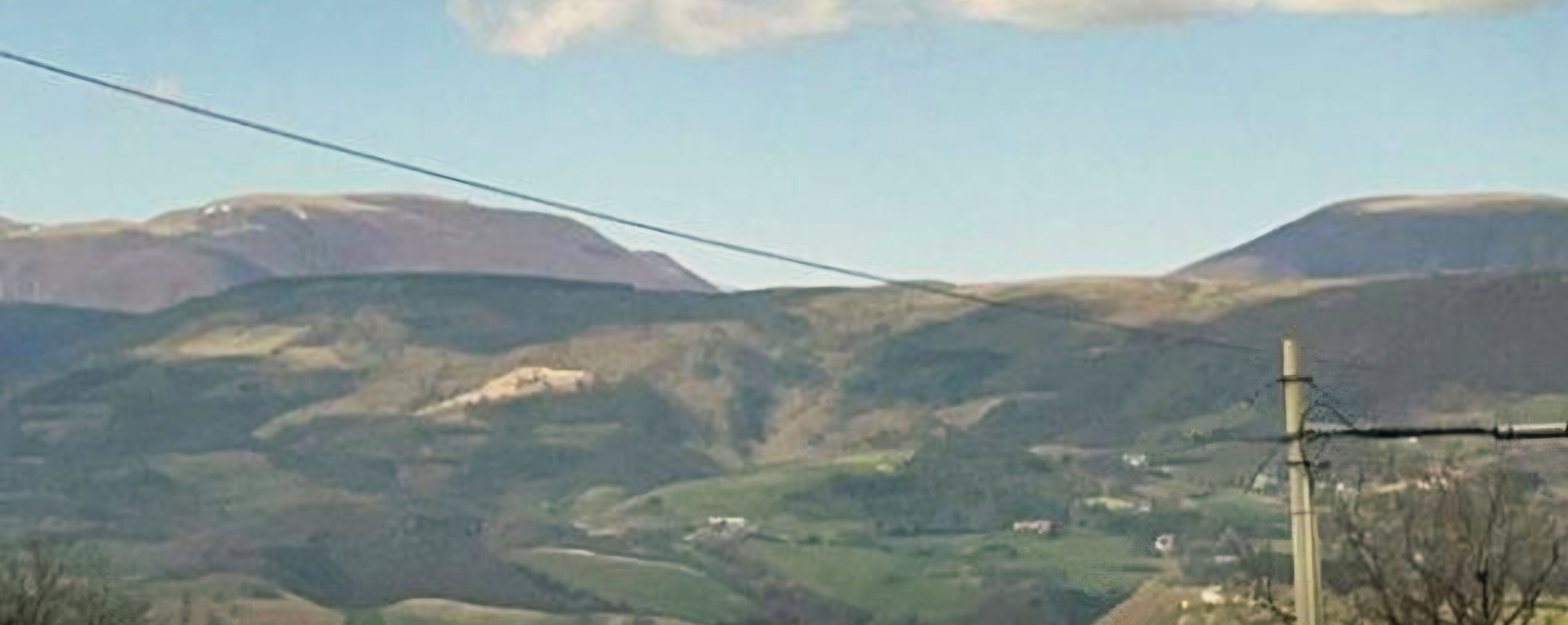 Un paysage rural caractérisé par des collines douces et un ciel dégagé.