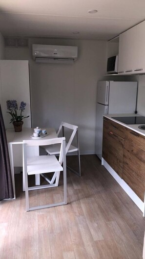 A compact kitchenette with a microwave, refrigerator, and a small dining area with a table and chairs. - In Country Luxury Lodges (Sentino)