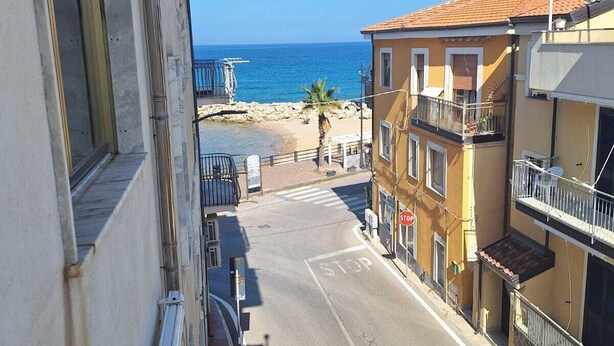 A street view with a clear view of the sea and a beach in the distance. - Seafront apartment in Santa Maria di Castellabate near the Pepi Promenade (Santa Maria di Castellabate)