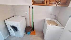 A compact kitchen with a washing machine, a small sink, and a cabinet. - Seafront apartment in Santa Maria di Castellabate near the Pepi Promenade (Santa Maria di Castellabate)