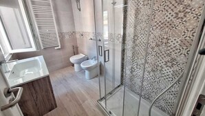 A modern bathroom with a glass shower enclosure, a toilet, and a sink. - Seafront apartment in Santa Maria di Castellabate near the Pepi Promenade (Santa Maria di Castellabate)