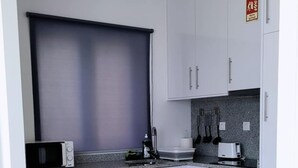 A compact kitchen with white cabinets, a microwave, a toaster, and a stove. - Loreto Apartment (Bragança)
