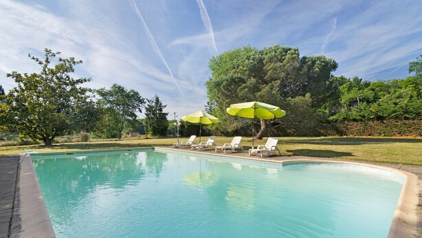 A swimming pool with lounge chairs and umbrellas, surrounded by trees and a clear sky. - Holiday Home "Le Pigeonnier" with Private Pool (Saint-Pompon)