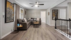 A modern living room with a gray sectional sofa, a coffee table, and a ceiling fan.