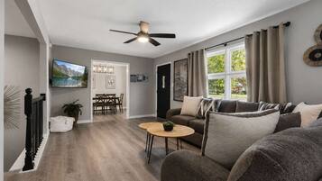 A modern living room with a sofa, a coffee table, and a dining area with chairs.