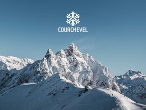 Paisagem montanhosa coberta de neve com um logotipo e a inscrição "COURCHEVEL".
