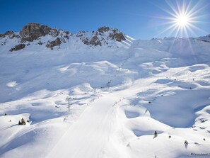 Paisagem montanhosa coberta de neve, com teleféricos e céu claro.