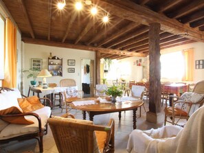Una habitación acogedora con techo de madera, muebles de mimbre y una mesa de comedor con sillas.