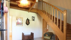 Ein geräumiger Raum mit einer Holztreppe, einer Bank und zwei Korbsesseln.