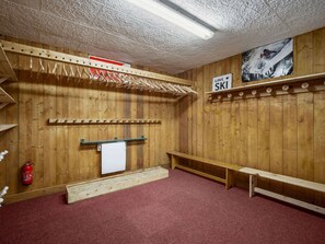 A ski lodge with wooden walls, a red carpet, a bench, a ski sign, and a fire extinguisher.