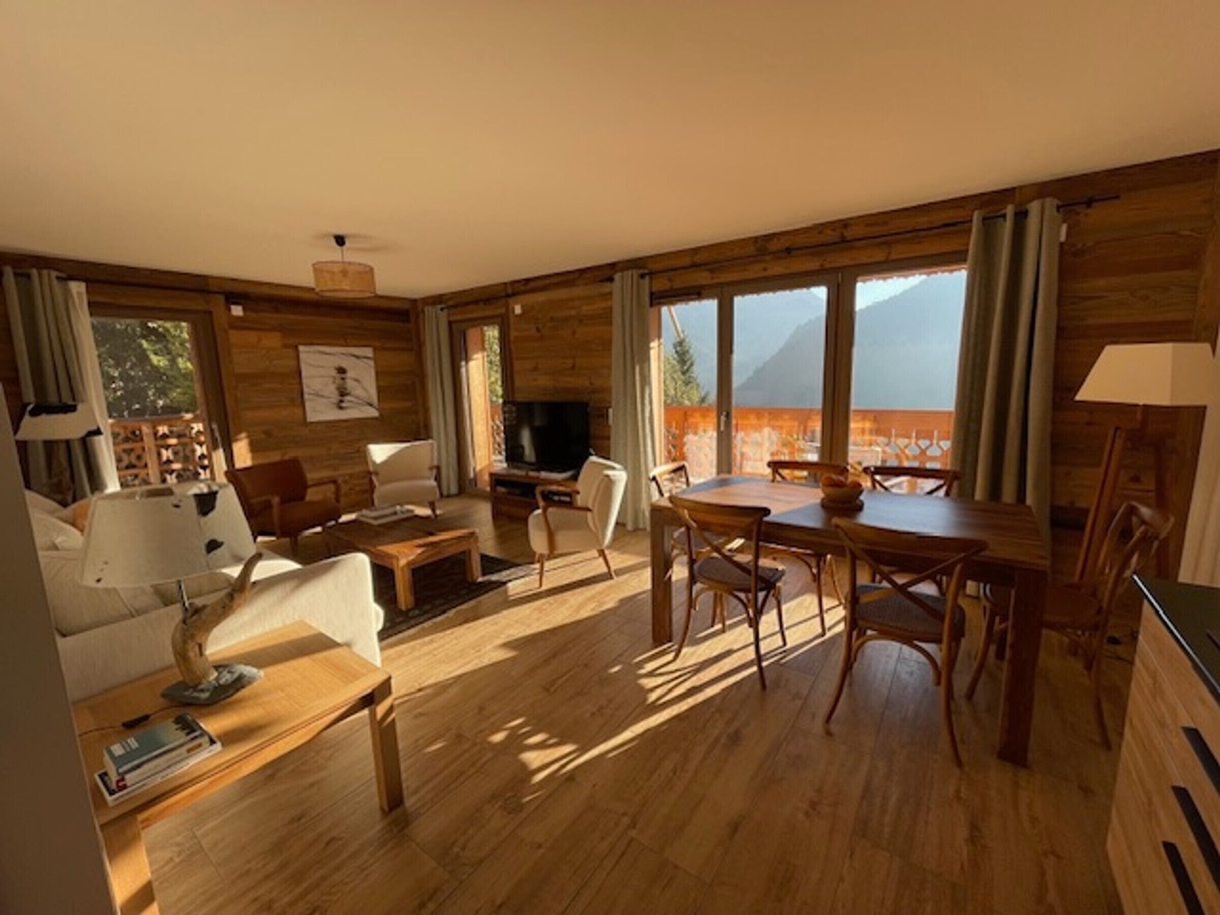 Un ampio soggiorno con finiture in legno, una zona pranzo e grandi finestre con vista sulle montagne.