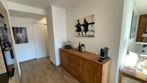Una cucina compatta con mobili in legno, una macchina per il caffè e un quadro appeso al muro.