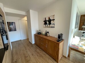Eine kompakte Küche mit Holzausstattung, einer Kaffeemaschine und einem Bild an der Wand.