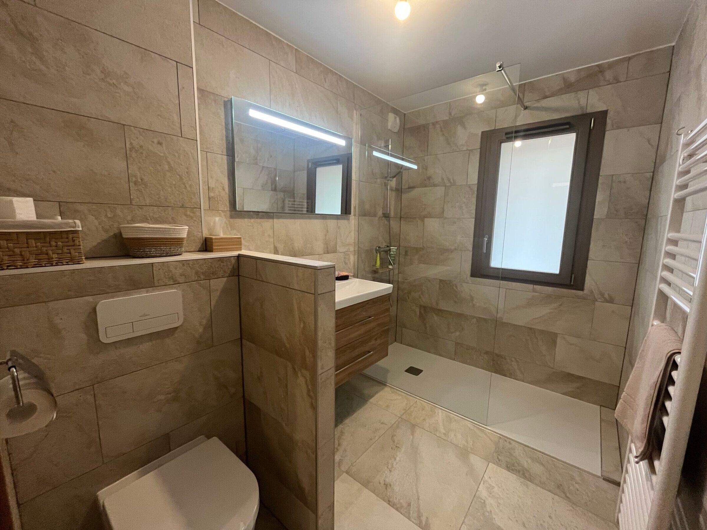 A modern bathroom with a shower, toilet, and vanity.