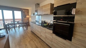 Una cucina moderna con mobili in legno, forno integrato e zona pranzo con tavolo e sedie.