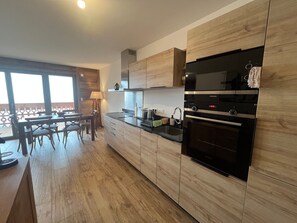 Eine moderne Küche mit Holzausstattung, einem Backofen und einem Essbereich mit Tisch und Stühlen.