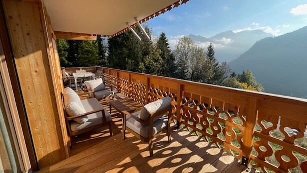 Un patio in legno con posti a sedere all'aperto e vista sulle montagne.