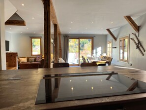A modern interior with a dining area, a sofa set, and a large window with a view of trees. - Renovated chalet in Samoëns, near center, ski bus (Samoëns)
