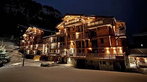 Un edificio de madera de varios pisos con balcones, probablemente un hotel, ubicado en la ladera de una montaña.