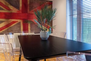 A dining table with a potted plant, clear chairs, and a Union Jack wall in the background. - Toast Stays - Gilmonby Grove (Middlesbrough)