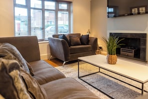 A modern living room with a sofa, armchair, and a fireplace. - Toast Stays - Gilmonby Grove (Middlesbrough)