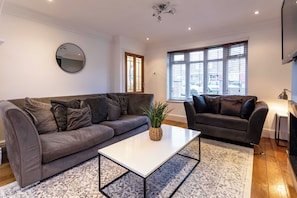 Ein modernes Wohnzimmer mit einem grauen Sofa, einem weißen Couchtisch und einem gemusterten Teppich.