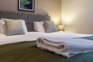 A neatly made bed with pillows and a folded towel, a headboard, and a framed picture on the wall. - Toast Stays - Gilmonby Grove (Middlesbrough)
