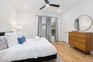 Un dormitorio con cama, cómoda, ventilador de techo y ventana con cortinas.